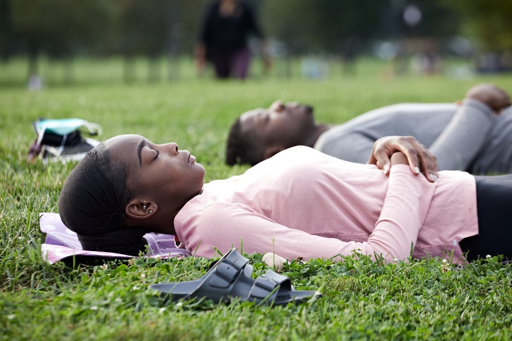 Two people lying in grass with their eyes closed.