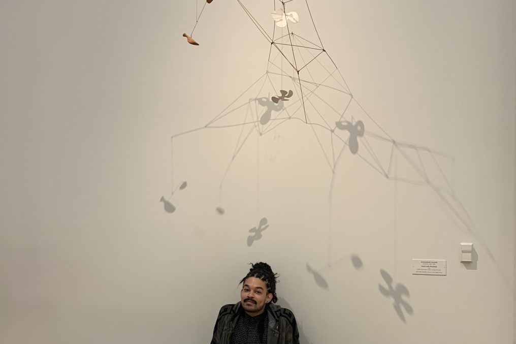 One person seated alone with a wire sculpture.