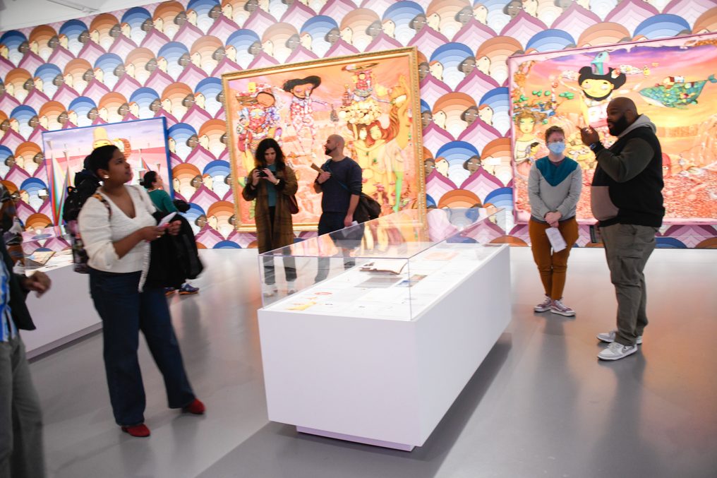 A group at a mural wall, seen wide.