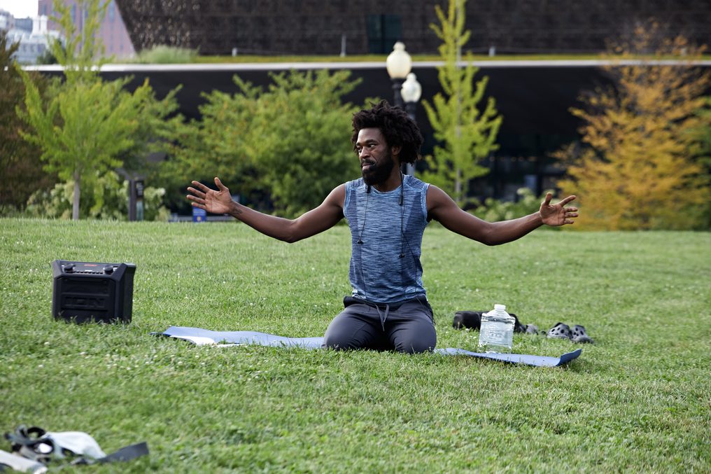 Charles Muhammad kneeling at the front of an outdoor class.