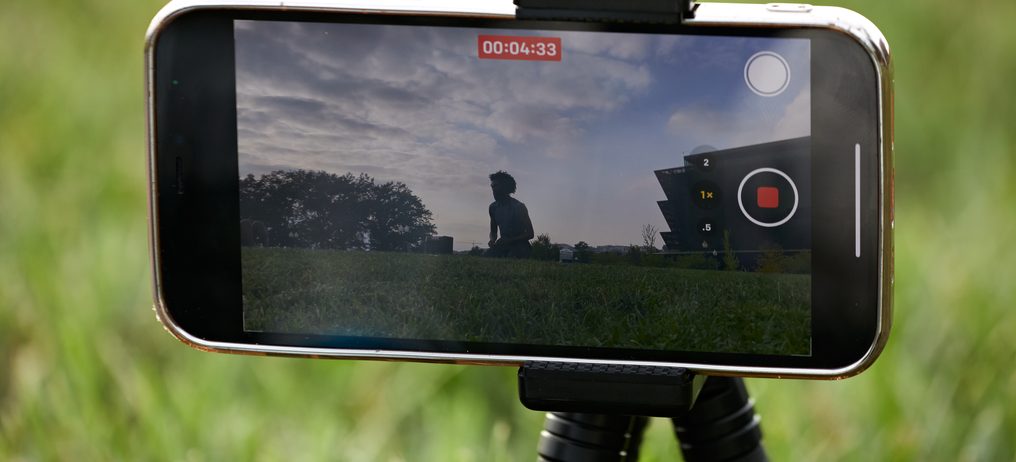 A phone on a tripod records an outdoor yoga class in progress on the National Mall.